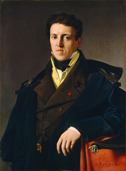 Shown from about the waist up, a man with pale, peachy skin, wearing a marine-blue greatcoat over several layers of clothing, looks out at us in this vertical portrait painting. The man’s body is angled to our left, and he looks at us from the corners of his dark brown, hooded eyes. He has an oval face with a slightly jutting chin, a long, straight nose, and his full-lipped mouth is lightly pursed. He is lit from our left, casting the right ear and side of his face in shadow. His chestnut-brown, wavy hair is short, and brushed forward over the ear we can see. Several shirts and coats are layered over his shoulders. Closest to his skin, a high-collared white shirt, with points reaching past his jawline, is tied with a wide, black neckcloth. Next is a custard-yellow garment, also with a high-neck, perhaps a vest. Over that he wears a brown coat with wide, pointed lapels. A bright, scarlet-red oval is fastened to one buttonhole on the lapel to our right, and a gold and rose-pink ornament peeks out from the bottom hem at his waist. Finally, the blue greatcoat has an elbow-length cape, and nearly falls off his shoulders. Fabric across the back of the collar is a hood lined with dark silver satin. He props his left elbow, to our right, on a table or ledge, and that wide cuff is rolled back over the white edge of this shirt. He wears a gold band on the pinky finger of that hand. The ledge is draped with a deep, marmalade-orange cloth. Gold tassels dangling from the end of a scrolled, bound document hangs off the edge of the ledge, near the man’s wrist. The background deepens from sage green along the lower left edge of the painting to fawn brown around the man’s head. The artist signed and dated the lower right corner, “Ingres. Pinx. Rom. 1810.”