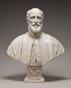 This free-standing, white marble sculpture shows the head, shoulders, and upper chest of a balding, bearded man. In this photograph, his body faces us and he looks straight ahead. Bushy eyebrows arch low over deeply set eyes, and his forehead hollows inward at his temples. He has high cheekbones and the skin of his cheeks draws slightly in. His thin lips are set in a straight line within a full beard. His high-necked robe falls slightly open over his chest and is cut also away over the shoulders to show the crinkled fabric of the garment beneath. The bottom edge of the sculpture curves upward in a very shallow U across the bottom, and is supported by a square pedestal foot decorated with scroll designs. The background behind the bust lightens from charcoal gray along the top edge to pale gray across the bottom, and the sculpture casts a shadow behind its base.
