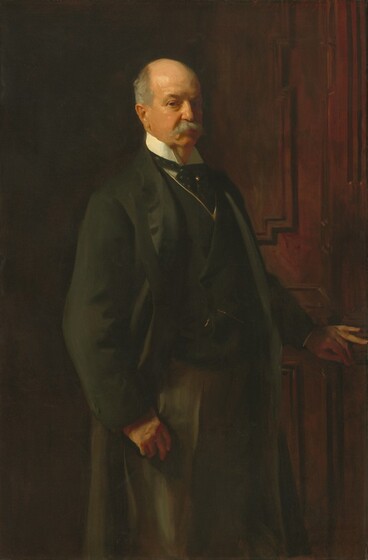 Shown from the knees up, an older, pale-skinned man stands with his body angled to our right as he looks at us from the corners of his eyes in this vertical portrait painting. His short fringe of hair around a balding head and his bushy moustache are steel gray, and he gazes at us with brown eyes under thick brows. A long, hooked nose and small red mouth are set in his jowl-lined face. He wears a long, fern-green coat with a matching vest trimmed in gold over a white shirt. A polka-dotted, pine-green cravat is tied around the standing collar and held in place with a gold pin. Two copper-colored brushstrokes near his waist suggest a pocket watch chain. The hand closer to us hangs by his hip with the thumb hooked into the pocket of his trousers, which are loosely painted with long strokes of olive and sage green. His other hand rests on the mahogany-brown wooden door that fills the space beyond him. Inset panels on the door are outlined in darker brown to create stepped, geometric shapes. The man is warmly lit from the upper left and the background is in shadow. The artist signed and dated the painting in the upper right, “John S. Sargent 1902.”