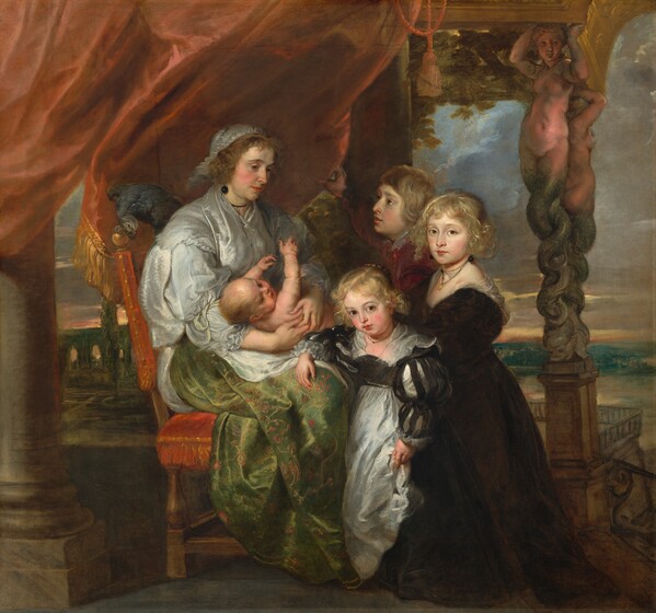 A seated woman with an infant on her lap and three children are clustered on a terrace overlooking green hills and a body of water in this square painting. They all have pale skin with flushed cheeks. The group is centered in the composition, and the woman sits to our left, facing our right, almost in profile. The wooden chair is upholstered in scarlet-red fabric and a large slate-blue bird perches on the backrest. Gold-edged, red drapery hangs behind the woman, suspended from stone columns on either side of her. The woman’s brown hair is covered by a frilly, silvery-gray cap with a matching shawl layered over a short, three-quarter sleeve jacket. Her fern-green skirt, covered with a pattern of coral-red flowers and gold vines, gleams in the soft light coming from behind us. A thin black band encircles her neck, and a round, black earring dangles from the ear we can see. She bows her head slightly and gazes down at the children. The infant lies across her lap with its head coming toward us, its chubby arms reaching up to the woman while turning to look at the three standing children. They appear to be a young boy and two girls, and they all have blond hair, large brown eyes, and delicate rose-red mouths. They crowd together at the woman’s knees. The boy is taller than the girls and stands behind them, visible from the shoulders up. He is dressed in red garments and stands almost in profile to gaze up at the woman. The girls turn their heads to look directly at us. At the center of the trio, the taller girl wears a long, voluminous brown gown. Her hair is pulled back and long ringlets frame her face. She also wears round black earrings and two delicate black cords around her neck, one of which holds a gold ring. At the front, the shortest girl wears a black and white gown with a sheer neckerchief along neckline, and she rests one arm across the woman’s lap. The girl’s long, puffy, black sleeves are slashed to create openings for white fabric to show through. Her hair is also upswept with ringlets framing her face. To the right of the group is a column made of two creatures with pink female heads, faces, and nude torsos with scaly, olive-green, twisting, snake-like legs. One creature faces us and the other faces our right. The sky beyond the terrace is filled with clouds that transition from slate gray at the top to tan and rust orange where it meets the distant hills.