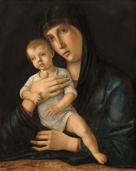 Shown from the waist up, a young woman holds a baby up against her chest in this vertical painting. They both face us and have pale skin. The woman holds the baby against the right side of her chest, to our left, and she tips her slender, oval face toward him. She looks at or toward us with hazel eyes under thin, arched brows. She has a long nose, smooth cheeks, and a dusky-pink bow mouth. The neckline and the cuffs of her garnet-red gown peek out from beneath a dark, spruce-blue, gold-edged mantle that covers her head and wraps around her. One forearm rests along a surface marbled in tomato red, coffee brown, and tan. With her other hand, she supports the chest of the baby, who wears a long, putty-grey robe with a high neckline. The sleeves and hemline are pushed up to reveal his pudgy arms and the leg we can see. The infant has wavy, reddish-brown hair, a petite nose, pale coral, bow mouth, and large, green eyes under faint brows. His head is also tilted to our left and he gazes off in that direction. His exposed left leg, on our right, dangles over the woman’s arm, his toe nearly brushing the tabletop. His other leg is tucked within the folds of her mantle. The elegant fingers of her free hand curl around the child’s hidden leg. The pair are warmly lit from the upper left and set against a dark, earth-brown background.