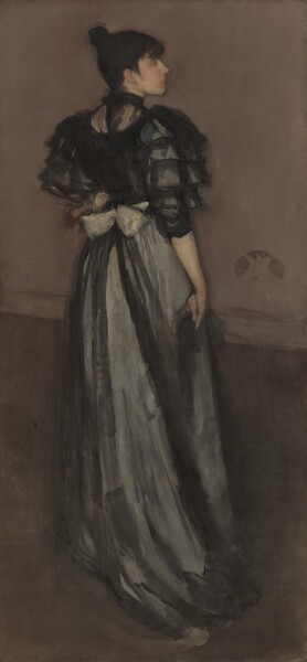 A woman stands with her back to us wearing a silver and black gown as she turns to look to our right in profile in this vertical portrait painting. We look slightly down onto the woman, and her features are painted with blended brushstrokes, making some details indistinct. She has pale, peachy skin, a straight nose, a strong chin, and her pink lips are closed. Black bangs brush the temple we can see, and her hair is pulled up into a bun high on the back of her head. Her black bodice has elbow-length, ruffled silver sleeves, which seem to be overlaid with translucent black material gathered in tiers. More gauzy black material covers her upper back to a high, black collar. A pearl-white bow at her lower back is nearly the width of her waist. The silver fabric of her long skirt drapes to and on the floor in a short train in deep folds. The woman’s right arm hangs by her side, and she holds what might be a piece of black fabric. A baseboard angles in a shallow diagonal down to our right across her hips. The wall above is smoky mauve-purple and below is charcoal gray. The shape of a butterfly within a darker oval is on the wall just to our right of the woman’s wrist.