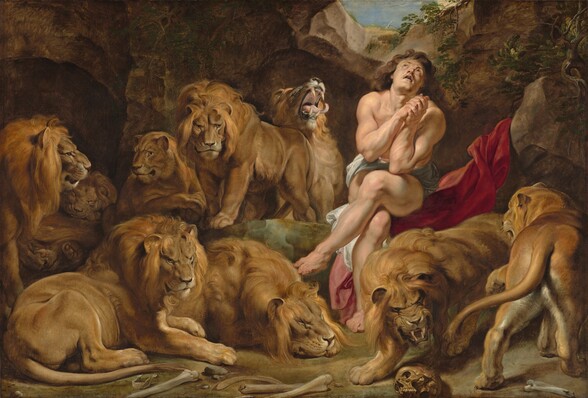 As if sitting in an underground cave, we look onto a scene with a nearly nude man, muscular with pale, peachy skin sitting among seven male and two female lions in this horizontal painting. The man sits to our right of center with his legs crossed, elbows close to his body with hands clasped by his chest, head tipped back looking up towards a small opening above. He has long, wavy, chestnut brown hair and has dark eyes. A white loincloth covers his groin and he sits on a scarlet red swath of fabric draped up over a rock next to him. The nine lions stalk, sit, or lie down around the man. One male lion next to the man, to our left, opens his mouth with his head thrown back, curling tongue extended beyond long fangs. A human skull and other bones are strewn on the dirt ground close to us. The rocky cave curves up around the animals and man to a narrow, round opening showing blue sky above.