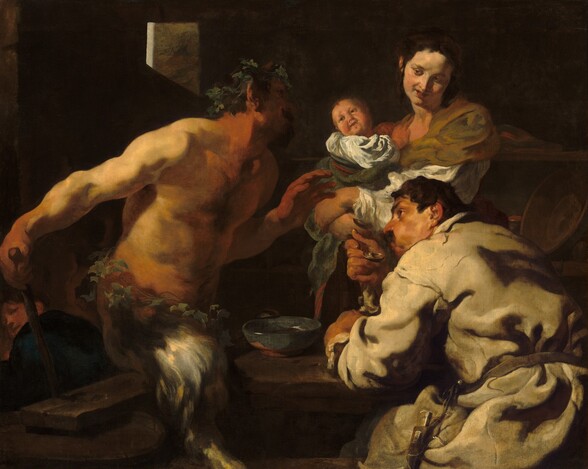 Shown from the about the thighs up, a man, a woman holding a swaddled baby, and a satyr, with a man’s torso and goat’s legs, sit and stand around a table in a deeply shadowed room, filling this horizontal painting. All the people have light skin and dark hair, and are lit dramatically from our left. To our left, the bare-chested satyr faces our right in profile as he leans toward the table, looking up at the woman. He wears a crown of leaves and has a dark goatee. Almost lost in shadow, a sable-brown horn juts up from his temple. Light falls across his bare shoulders, and his hands and neck are ruddy. Another ring of leaves encircles his waist over the silvery gray fur of his goat’s legs. He holds his left hand, farther from us, in front of his chest with his open palm facing the couple to our right. His other hand rests at the top of a wooden staff behind his right hip, closer to us. The staff disappears behind the plank resting across at least one wooden barrel that presumably acts as the bench that he sits on or hovers slightly over. The second man sits at the table to our right, his back mostly to us as he looks over his left shoulder, up toward the satyr with his face in profile. One brow seems cocked over the dark eye we can see, and he has a prominent nose and a mustache. He wears a loose-fitting, long-sleeved, parchment-white garment tied around the waist. He blows across a soup spoon held to his lips, his cheeks puffed. He leans on his other arm, which rests on the tabletop near an ocean-blue bowl. Across the table, behind the seated man, a woman looks back at the satyr from the corners of her eyes, her coral-red lips curled up in a smile. Her body faces our left and she tilts her head to her left, our right, as she turns her face down toward that shoulder. Her dark brown hair is pulled up and back, and she wears an olive-green wrap over a white shirt. The baby she holds leans away from her chest to twist and look back at the satyr as well. A few details eventually emerge from the deeply shadowed background, including a fourth person tucked into the lower left corner, who looks back over a shoulder at us or the group. Light rims the corner of a window cut from a stone wall, and a few ceramic dishes and cups line two shelves to our right behind the woman.