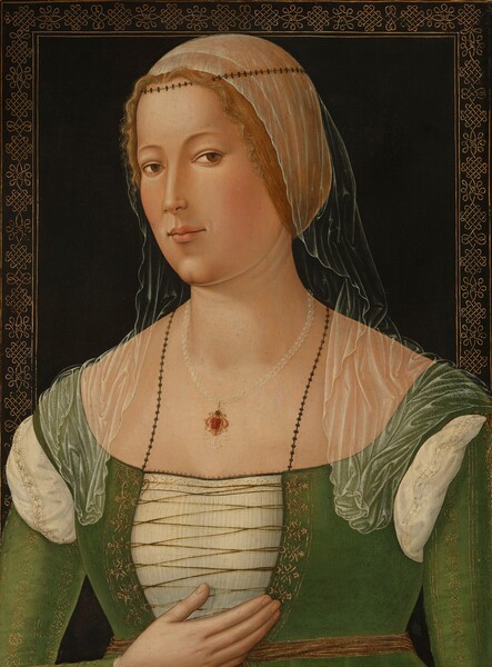 Shown from the chest up, this pale-skinned woman wears a transparent veil and a green gown laced up the bodice in this vertical portrait painting. Her shoulders and face angle to our left, and she looks at us from the corners of her brown eyes with her head tipped slightly away from us. She has faint, arched brows, a long, delicate nose, and a rounded jaw. Shallow dimples to either side of her pale pink lips suggest a faint smile over a cleft chin. Her blond hair is pulled back under a diaphanous veil, which is held in place with a band around the crown of her head. The veil falls in gossamer folds over her shoulders. The bodice and sleeves of her gown are asparagus green. The front is laced over a white shirt, and the white fabric has been pulled through at her shoulders where the sleeves would be tied to the bodice. The gold dress and the white chemise are edged with bands of floral, geometric patterns in gold, and a gold belt wraps around her waist. The pendant hanging from her pearl necklace has red and blue gems set in gold, with three more pearls hanging from the bottom. Another necklace looks like a chain of small, star-like forms, and it is tucked into her bodice. She holds her right hand, to our left, cupped near her chest, and her other arm hangs by her side, off the bottom edge of the composition. The background is black, and the edge of the panel is decorated with a band of gold, geometric, knot-like patterns. The gold border disappears behind the woman’s shoulders, which span the width of the painting.