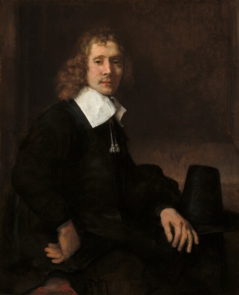 Shown from the hips up, a young man with pale skin and wearing ink-black clothing sits with his body angled to our right as he turns to look toward or at us in this vertical portrait painting. He looks out with green eyes under hooded lids. Light falls across his face from the upper left so his bumped nose casts a shadow on his high cheekbone. He has a wispy mustache over full, pink lips, which are slightly parted. His hair falls to his shoulders in soft auburn curls, framing his slender face. Two silvery tassels hang on cords from a tall, wide, flat, bright white collar, which contrasts sharply with the velvety black of his voluminous, long-sleeved jacket.  His left hand, farther from us, rests on his knee and the other hand is curled so the back of his knuckles press against his right hip, closer to us. A patch of crimson red near that hand could be a pillow on his chair. His hat rests, presumably on a table, just beyond his legs. The hat has a tall, tapering, conical crown with a flat top. The shadowy wall behind him is mottled with slate gray and caramel brown, with a slightly darker panel to suggest a shallow niche.