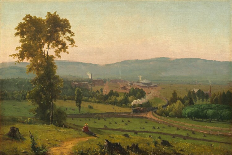 We look across and down into a valley with a person sitting near a tall tree and a train puffing smoke beyond, all enclosed by a band of mountains in the distance in this horizontal landscape painting. Closest to us, several broken, jagged tree stumps are spaced across the painting’s width. A little distance away and to our left, the person wears a yellow, broad-brimmed hat, red vest, and gray pants. He reclines propped on his left elbow near a walking path beside a tall, slender tree with golden leaves. The green meadow stretching in front of him is dotted with tree stumps cut close to the ground. Beyond the meadow, puffs of white smoke trail behind a long steam locomotive that crosses a bridge spanning a tree-filled ravine, headed to our left. The ravine creates a diagonal line across the canvas, moving subtly away from us to our left. The train has climbed out of the valley, away from a cluster of brick-red buildings. The most prominent structure is a train roundhouse, a large building with a high, domed roof to the right of the tracks. Smoke rises from chimneys on long, warehouse-like buildings, and a steeple and smaller structures suggest a church and homes to our left. Hazy in the distance, a row of mountains lines the horizon, which comes about halfway up the composition. The sky above deepens from pale, shell pink over the mountains to watery, pale blue above. The artist signed the work in tiny letters in the lower left corner: “G. Inness.”