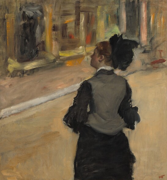 Shown from about the hips up, a woman whose pale face is deep in shadow stands with her back to us, wearing a black and gray dress and hat, in front of a colorful but loosely painted, indistinct background in this nearly square painting. She stands just to our right of center with her elbows bent, perhaps to clasp her hands in front of her. Her head is turned slightly towards us so we see the line of her forehead, nose, and chin almost in profile facing our left. Her auburn hair seems to be pulled up under a black hat that sits on the back of her head. Her high-necked, charcoal-gray vest-like bodice has a line of white at the neck, suggesting lace or an undershirt. The bodice covers a black shirt with ruffles that fall at least to her elbows, and the long dress drapes close along the contours of her legs. She looks to the far wall, which is painted with sketchy, visible brushstrokes in marigold orange, lemon-lime green, brown, black, and pale yellow to create the impression of paintings in gold frames. The artist signed the painting in dark red in the lower right corner: “Degas.”