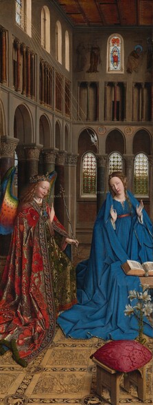 A woman and winged angel, both with pale, peach skin, are situated in a church interior in this tall, narrow painting. To our left, the angel has long, blond, curly hair, smooth skin, and is smiling. The wings are outlined in royal blue, and they blend from blue to green to yellow to crimson. The angel holds one hand, closer to us, up at chest height with the index finger subtly pointing upward. Holding a long scepter in the other hand, the angel angles their body toward the woman to our right. The angel wears a gold jewel and pearl-encrusted crown and a jeweled long, voluminous robe in scarlet-red and shimmering gold brocade. The neck and along the opening down the front are lined with pearls and jewels. The angel looks toward the woman, who wears a royal-blue dress tied with a red belt at the high waist. Her long brown hair is tied back but one tendril falls over her left shoulder, to our right. She kneels facing us with her raised hands facing outward. Her head is tipped a bit to our left, and she looks up and into the distance to our right with lips slightly parted. She kneels behind a book lying open on a low table. A vase of white lilies and a red cushion lies on the floor in front of the table, close to us. The floor is decorated with people and scenes outlined in black and set into square panels, as if inlaid with wood. The church behind and above the people has a row of tall, narrow arches with bull’s-eye glass windows. A walkway lined with columns runs above the arches, and sunlight comes in through arched windows under the flat wood ceiling. A white dove flies toward the woman on gold lines from a window at the upper left of the painting. Latin words painted in gold capital letters are exchanged between the people. The angel says, “AVE GRA PLENA.” The letters of the woman’s response are painted upside down and backward: “ECCE ANCILLA DNI.”