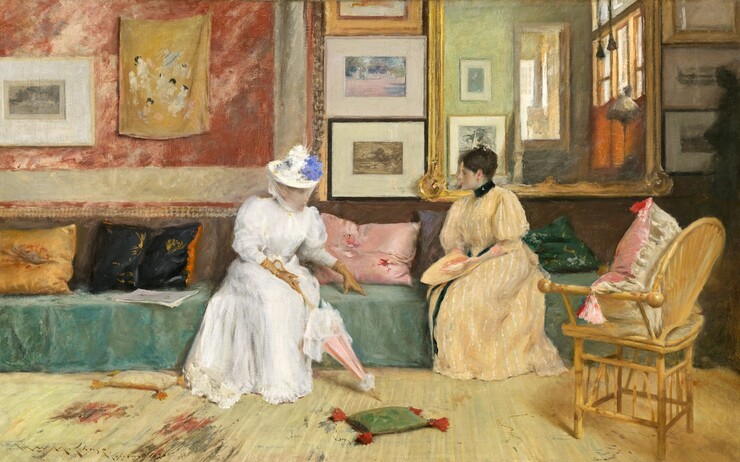 Two fair-skinned women sit facing each other on a long sofa centered on the wall across from us in a room warmly lit from the right in this horizontal painting. The woman on our left wears a white full-length dress trimmed with a ruffled hem and belted at the waist. The billowing sleeves narrow below the elbow and are tucked into long, fawn-colored gloves. She wears a brimmed hat topped with dabs of white and lapis-blue paint, presumably flowers, with a sheer veil covering her face and chin. Glints of gold at her wrists might be bracelets. Her lower body faces us but her head and torso turn to her left, our right, to face her companion. She leans forward, with her left hand slightly extended, and she rests her fingertips on the cushion between them. Her other hand, closest to us, holds the camel-brown handle of a closed tea rose-pink parasol trimmed with white. To our right, the second woman sits with her knees angled to our left as she turns her head in profile, looking at her companion. She wears a floor-length butter-yellow dress with white vertical stripes. The dress has a high black collar and a black ribbon wraps around her waist and falls down the front of the dress. Her sleeves billow at the shoulder and narrow below the elbow. Her dark brown hair gathered at the top of her head. She holds a flat object in the same butter yellow in her lap that may be a matching hat. The sofa spans almost the entire width of the center of the painting. Its seat is draped in moss and emerald-green fabric and emerald green, mauve and tea rose pink, black, and gold throw pillows are scattered along its length. The lower half of the wall behind them is a tawny brown while the upper half is divided into four sections. From left to right, a coral-red and off-white wall hanging fills the left side behind the woman in white. A framed artwork and mustard-yellow fabric with daubs of white, ash grey, and black hang from it. Moving right, a column of three framed artworks hang on the wall between the women. Next is a large mirror with a gilded frame that hangs behind the woman in yellow. At the far right is another column of three framed artworks. The room behind us is reflected in the large mirror, showing an amber colored wall with large windows and more framed artworks on the opposite wall. Steps leading up to another sunlit room are also visible. A wicker chair with a pink and white pillow sits in the lower right, facing the women at an angle. The floor in front of them fills the lower third of the composition and is covered with a vanilla-yellow carpet with areas of smoke grey and brick. Two small throw pillows with tassels lie at the feet of the woman in white. The tip of her parasol points to a small emerald-green pillow with tomato-red tassels lying on the floor between the women. To our left of the woman in white is a cream-white pillow with marigold-orange tassels. The scene is loosely painted, with details only hinted at. The artist signed and dated the painting in the lower left, “Wm. M. Chase. Copyright 1895.”