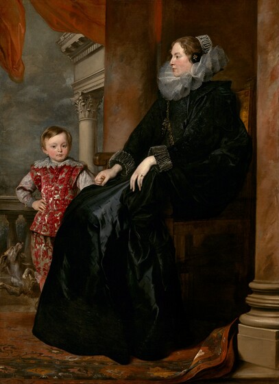 A woman wearing a voluminous black dress with a wide, ruffled collar sits holding the hand of a young boy, who stands next to her, in this full-length, vertical portrait painting. The woman sits with her body in profile facing our left, and she looks in that direction. The boy stands at her feet, behind her legs to our left, looking out at us. Both have pale, peachy skin with rosy cheeks, dark blond hair, and brown eyes. The woman’s hair is pulled back and covered with pearls, and a few short tendrils curl around her face. Her long black dress has puffed, black-on-black brocade sleeves and the skirt is cut with short, decorative slits. The skirt has a sheen where the light falls, suggesting it is silk. Her wide, stiff, ruffled collar is pleated into a figure-eight pattern around her neck and a thick gold chain loops over one shoulder to the opposite hip. The sleeves have wide, ruffled cuffs and she wears a gold ring with a slate-blue gemstone on the pinky finger of her right hand, closer to us. The boy’s small fingers wrap around the woman’s elegant right hand, farther from us. His body faces us and his other hand rests on his hip. His straight hair falls across his forehead and to his ears. His richly patterned suit has a crimson-red leafy pattern against gray satin, and the sleeves are also nickel gray. A wide, lace-trimmed collar rests along his shoulders. A dog frolics behind the boy, looking up at him with mouth open and tongue hanging out. The woman’s chair is framed by two stone columns streaked with rust red and taupe, and they extend off the top edge of the composition. A balustrade runs behind the boy along an opening beyond. The top corner of an entablature or lintel supported by columns is visible against a steel gray, cloudy sky. A red drape flutters above the people, along the top edge of the canvas, and the red-and-brown woven carpet below the pair kicks up at the base of the column closer to us.