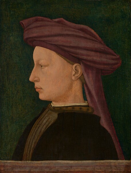 Shown from the chest up, a light-skinned man wearing a burgundy-red turban faces our left in profile against a dark background in this vertical portrait painting. He looks off to the left, and the eye we can see is light brown under a faint, possibly plucked eyebrow. He has a straight nose, and his full peach-colored lips are closed. There is the suggestion of a puffy area under the eye we can see, but the rest of his skin is smooth. His brown hair is mostly tucked under his turban, and a piece of fabric hangs down the back of his neck. A band of his white undergarment is visible at the high neck of his olive-brown shirt, which appears to be pleated or striped down the front. He also wears a black jacket, which covers his shoulder and most of his chest. A brown band across the bottom edge of the painting could be a wooden railing or ledge, behind which the man is shown. Cracks are visible across the painting, especially in the deep green background.