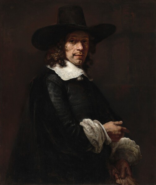 Shown from the hips up, a man with pale, peachy skin, dressed in a black suit and tall hat, looks at us from in front of a dark brown background in this vertical portrait painting. The man’s body is angled to our right, almost in profile, but he turns his head to look at us from the corners of his eyes under lifted brows. He has rounded nose, a thin mustache over wide, pink lips, and a deep cleft in his chin. His face is fleshy under his eyes and along his jawline, and he has a slight double chin. The wide brim of his tall black hat casts a shadow across his eyes. Shoulder-length, brown, curly hair falls on a wide, lace-edged bright white collar, which lies flat across his chest and shoulders. Light glints off his black jacket, suggesting a sheen. Wide white, disk-like cuffs encircle his wrists over puffs of voluminous white sleeves that gather on his forearms. A black, velvety cape drapes from the shoulder closer to us and down across his waist. He points to our right with his right arm, closer to us. The fawn-brown glove or pair of gloves he holds in his other hand by his far hip is cut off by the bottom edge of the canvas.