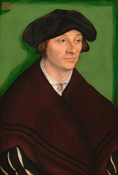 Shown from the waist up, a clean-shaven man with pale, peachy skin is dressed in black and burgundy red in this vertical portrait painting. His shoulders are as wide as the composition and his hat nearly touches the top edge, so he almost fills the painting. His body and face are angled to our right, and he looks off in that direction with hooded brown eyes under slightly raised brows. He has a long, bumped nose, high cheekbones, the hint of a five-o-clock shadow, and his pale pink lips are closed. His hair is cut straight across at ear length, and fuzzy sideburns come down to his jawline. A wide, soft black cap curves down either side of his head to ear level. He wears a white shirt with a delicate black pattern on the neckline, which is tied with a thin black ribbon. A voluminous dark red shawl or wrap has two black bands along the bottom hem, and it engulfs his sloping shoulders. In the lower corners of the painting, we see long black sleeves under the wrap. The sleeves have slashes to allow the white undergarment to show through. He is set against a lime-green background and illuminated by bright light from the upper right, which creates a darker green shadow behind him, to our left. The artist signed the painting with a symbol on a small, light brown panel, which appears to be affixed to the back wall in the upper left corner of the painting. The date, “1522,” appears over a winged serpent holding a ring in its mouth.