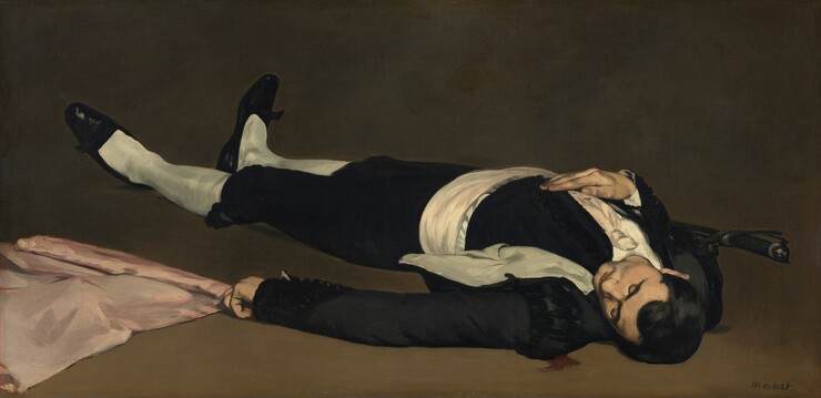 From a low perspective, we look at a man wearing black and white, lying on the ground with a pink flag beside him in this long, horizontal painting. We look onto the top of his head and his feet reach into the upper left corner of the composition, so he nearly fills the painting. His dark hair is cut short and gleams softly in the light from the upper left. His head has fallen toward his left shoulder, and his eyes are closed. He wears a black jacket and knee-length black pants. His jacket falls open to show white lining, and he wears a wide, white cummerbund and white stockings. His black, loafer-style shoes have pointed toes and possibly a bow at the bridge of each foot. He man’s right hand, farther from us, rests on his chest, and a black-handled sword or dagger is tucked into that elbow. That hand and his white tie are speckled with red blood. More blood seeps on the peanut-brown floor near the man’s left shoulder, closest to us. The man wears a gold ring on the pinky ring of his left hand, which lies along the ground and rests on or near the pale pink flag, which continues off the bottom left corner of the painting. The brown ground is lighter along the bottom of the painting and deepens to peat brown farther back, along the top edge. Brushstrokes are visible in some areas, especially in the white parts of the costume and the flag. The artist signed the painting in the lower right, “Manet.”