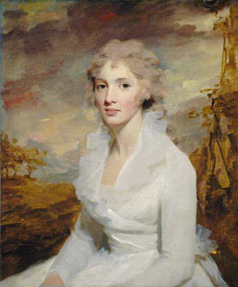 Shown from the hips up, a pale-skinned woman wearing white sits facing us against a golden-toned landscape background in this vertical portrait painting. The woman’s body is angled to our left, but she looks at us steadily from the corners of her large eyes. The slate-blue irises have some touches of hazel. Her cheeks are tinged with pink, she has a long nose, and her full pink lips are closed. Her ash-brown hair is pulled loosely back and falls in curls around her heart-shaped face. A translucent white ruffle flares around the neckline of her opal-white, long-sleeved dress. The bodice wraps across the front to a bow at her lower back. The landscape immediately behind her is loosely painted with gold and mustard yellow. Mountains in the deep distance along the horizon are painted broadly with smoky blue and purple. A band of plum-purple clouds stretches across the top of the painting in front of higher, pale yellow and blue clouds.