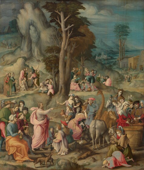 About fifty pale-skinned men, women, and children along with a giraffe, ox, and other animals gather in groups across a hilly landscape in this vertical painting. The people wear robes or dresses in shades of carnation pink, honey orange, sky blue, ruby red, leaf green, or golden brown. The people’s skin is painted pearl white or, in a few instances, tinged with gray. A crowd of eight men and women gather in the lower left quadrant behind a man who points to the right with a stick. Others sit on the ground or on rocks, stand at barrel-sized urns, or bend to the ground. A porcupine, white rabbit, black bear, cow, cheetah-like animals, and several others are spaced along the foreground, close to us. The gathering continues into the distance to the right, where a path leads to a cluster of buildings along a jagged coastline. Craggy mountains rising from water line are shaded aquamarine blue under a cloudy sky. A few tall, spindly trees grow up the center of the composition, and a tall, rocky outcropping takes up most of the upper left quadrant.