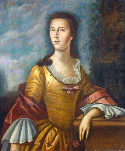 Shown from the waist-up, a pale-skinned woman wearing a gold-colored gown and a muted dark pink shawl stands before a hazy landscape in this vertical portrait painting. Her body is angled slightly to our right, but she turns her face to our left as she looks at us from the corners of her dark gray eyes. She has an oval face with low, straight eyebrows, a long nose, prominent chin, and her thin, pale pink lips are closed. Her brown hair is pulled back and a lock curls over her right shoulder, to our left. Her low-cut bodice is lined with filmy ruffles and has a pink bow at the front center. The bodice fits tightly to the waist, where the full skirt flares out in deep folds. The sleeves end at the elbows with broad, ruffled cuffs. A dusky rose-pink shawl wraps around her back and over her elbows. She rests her left arm, to our right, on a ledge and holds a dark pink flower in that hand. The background has a suggestion of a structure nestled in dark trees to our right and a sky mottled with clouds across most of the picture.