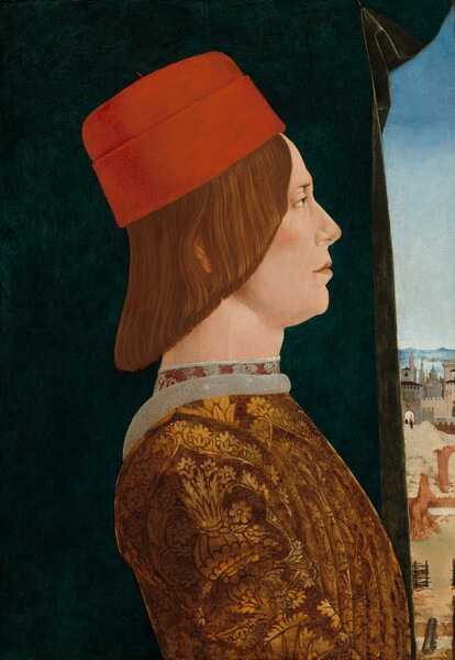 The head and chest of a clean-shaven, pale-skinned man is shown in profile facing our right, in front of a curtain opening onto a sliver of a distant landscape in this vertical portrait painting. The man’s eye we can see is hazel under a thin brow, and he has a straight nose over a closed, peach-colored mouth. A crease running from the side of his nose to the corner of his mouth is lightly shaded, and his cheek flushes light pink. His straight, auburn-brown hair is cut to angle from his brow down to his neck. He wears a tall scarlet-red cap and a brown and gold tunic pleated in vertical folds down the front. The tunic is patterned with stylized leaves and vines in gold against the brown background. The neckline is lined with smoke gray, and the high neck of a garment beneath is patterned with gray leaves against brick red. The marine-blue, nearly black, cloth behind him covers most of the background. A narrow view along the right edge of the composition opens onto a landscape with the ruins of a terracotta-colored gate and city wall closer to us, though still deep in the distance. Even farther back is a walled town with gray and pale peach towers and crenellated walls. Spires are silhouetted against azure-blue mountains, hazy along the horizon in the distance, under a pale, ice-blue sky.