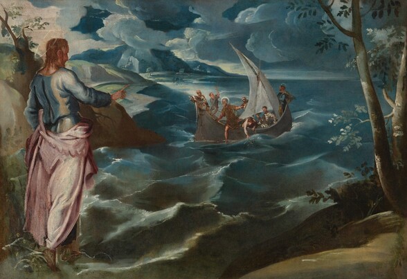 A man stands at a coastline with his back to us, gesturing toward a group of seven men sailing on the rolling sea in this horizontal painting. All the people have pale, peach skin. The man standing near us to our left wears a light blue tunic under a shell-pink garment that drapes around his hips and falls to his ankles. A thin gold halo encircles his head over curly brown, shoulder-length hair. Green land extends along the foreground close to us, and trees rise to either side. It is unclear whether the man stands on the land or on the water with bare feet. His body is angled away from us and to our right as he looks and gestures with one arm raised toward the boat on the water beyond. Choppy waves and swirling, dense clouds ranging from topaz to navy blue dominate the landscape. Each of the seven men in the sailboat does something different. For instance, one leans over the edge to grasp a fishing net while another pulls a rope for the sail. Two of the men have white halos. One stands at the back of the boat looking into the far distance and the other begins to step onto the surface of the water.