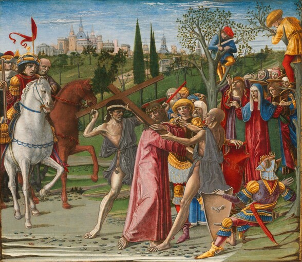 About two dozen men and women are gathered mainly in three groups in a grassy landscape in this nearly square panel. The action revolves around a man, Jesus, carrying a cross at the center of the composition. The people all have pale skin and wear robes, dresses, or tunics tomato red, cobalt blue, spruce green, deep yellow, gray, or white. Jesus wears a rose-pink robe, and blood trickles across his head from a ring of thorns thrust down over his shoulder-length brown hair. His flat, disk-like halo is gold with a red cross like a plus sign, and a tall wooden cross is braced across one shoulder. Two gaunt men in gray tunics jab and jeer at Jesus, mouths pulled back to show their teeth. A group of about seven men look on from over Jesus’s shoulder, including one man with gold-colored hair and gold armor. Another armored man wearing a helmet lies back on a rocky outcropping low to the ground in the lower right corner. The second group gathers behind three people also with halos to our right. The woman at the front center holds her hands out, palms up. Her lapis-blue cloak covers her head over a white veil and falls to her feet over a ruby-red dress. A woman with loose, blond hair looks up and raises her hands overhead to our left, and a fresh-faced young person stands to our right. One more person in the crowd of about six people behind this trio has a halo as well. Two boys perch in trees over this group, looking down between forks in the branches. The third group is to our left, and they gather behind a pair of men on white or brown horses. Pebbles are strewn on the dirt ground under the bare feet of Jesus and his tormentors. Grassy fields dotted with trees stretch into the distance to a town of spires, towers, and turrets on the horizon, which comes about three-quarters of the way up this composition. A few thin clouds skit across the blue sky above.