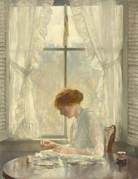 A light-skinned, red-haired woman sits in profile facing our left in front of a window, sewing at table in a room bathed in sunlight in this vertical painting. The loosely painted scene is dominated by slivery grays, cream, and ivory white. She faces our left with her head tipped slightly away from as she looks down at her hands. Her face is in shadow but her pale cheeks are deeply flushed, and her neck and arms are tinged with pink. Her cream-white dress has sheer elbow-length sleeves covered with a stylized floral pattern. Shadows are created with soft, steel blue. She sits on a wooden chair with a curved back. She rests the arm closer to us on a bundle of white material that lies on the gleaming, round, wood table that separates us from her. Her other hand reaches forward with the thumb and index fingers touching. A spool of white thread sits on the table near her hands and, on the other end, near her elbow, is a small vase with a round black base and touches of scarlet, moss green, and baby blue on the neck. There are streaks of olive green and mustard yellow on the tabletop that hard to interpret. The window behind her fills most of the canvas. Ruffled white curtains are pulled to each side with a sash, and shutters are swung inward. The view is loosely painted and seems hazy, but copper-brown and gold strokes could suggest trees with slate-blue buildings in the near distance. The artist signed and dated the upper left corner, “JOSEPH-DE-CAMP-1916.”
