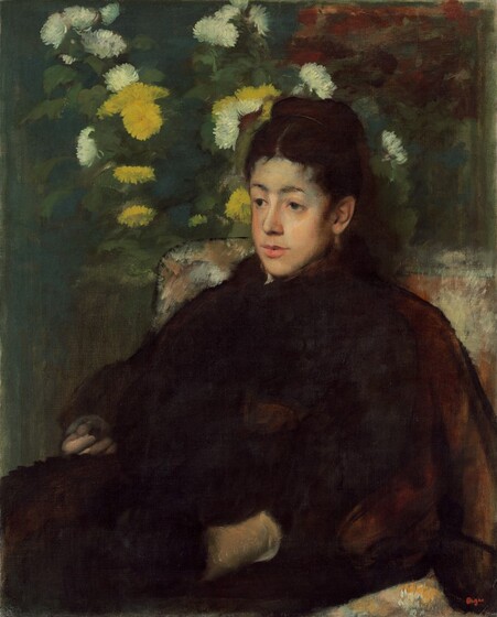 Shown from the lap up, a young woman with pale skin, rosy cheeks, dark eyes, and upswept chestnut-brown hair sits in an upholstered chair angled to our left and she looks in that direction in this vertical portrait painting. Light falls directly on her oval-shaped face, and she has a pointed chin and a straight nose. Her dark eyebrows are arched and though her eyes initially look dark as well, closer inspection reveals a sliver of silvery blue iris around the eye closer to us. Her full, pink mouth is slightly parted. She wears a brown, perhaps fur, shawl behind her shoulders over her long black dress. A few touches of rust red on the sleeve closer to us suggests a floral pattern but details are mostly lost in this dark area. She wears parchment-white gloves and her left hand, closer to us, appears to be tucked into a pocket or into a fold of her skirt so only the wrist is visible. She cups her opposite hand, perhaps cradling a small object. The fabric of the chair is painted with touches of burnt orange and ivory. Canary-yellow and white flowers dance around her head, presumably cascading from a vase on a table behind her. Most of the background, especially along the left edge, is painted with a field of stone blue but an area of loosely painted terracotta red above her head suggests a patterned wallpaper or more flowers.