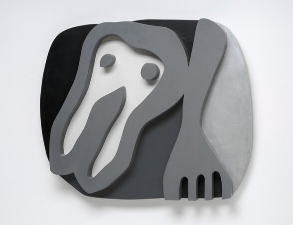 An almost cartoonish tooth-like form and a fork float against a roughly oval field in this abstracted wooden sculpture. Presumably the shirt front of the title, the tooth-like form takes up the left half of the composition. It has a rounded top with two pointed root-like legs below, and has two dots like eyes near the top. The fork to our right points downwards and the four tines are cut off by the bottom edge of the composition. The shirt front, dots, and fork are carved and painted nickel gray so they look like thick outlines in low relief. The background to our left and over the shirt front is black. The area between the shirt front and fork is dark gray, and the field to our right of the fork is silvery gray.