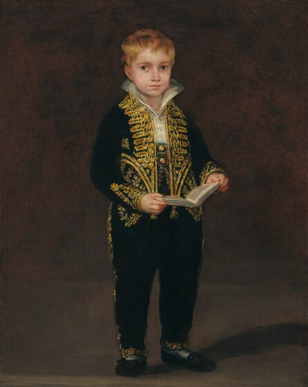 A young boy with pale skin, wearing a black suit with densely pattered gold trim and decoration, stands holding an open book in front of a brown background in this vertical portrait painting. His body is angled slightly to our right, but he looks at us with large, slate-blue eyes. He has a round face, a wide nose, and his full, peach-colored lips are barely parted. Short blond hair falls in tousled bangs across his forehead. A tall, oyster-white collar flares up in a wide V along the sides of his neck. His hip-length, long-sleeved black jacket has gold trim and decoration down the open front, along the bottom hem, and at the cuffs. His pants have a high waist, meeting the buttons of the white shirt at his chest. There are two gold buttons on his pants near the waist, framed by his open jacket. Gold trim continues down the sides of his long pants and around the leg openings. He wears black, loafer-style shoes with gray or white stockings or socks. He is lit from our left so casts a shadow to our right, in the dark brown room in which he stands.