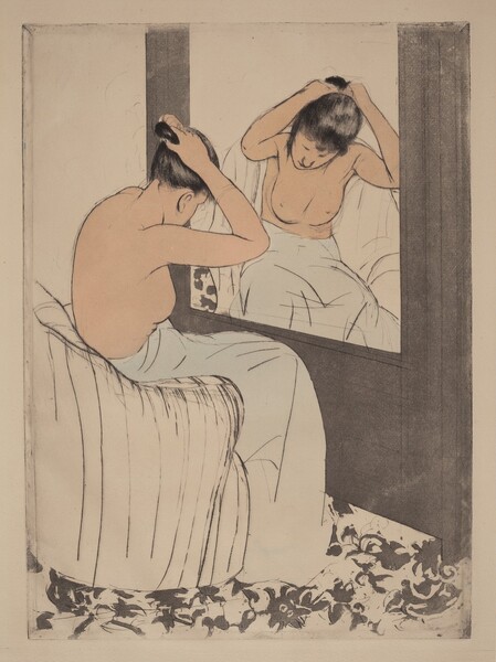 A pale-skinned woman, nude from the waist up, gathers her hair in her raised hands as she sits before a mirror in this vertical, colored print. The large mirror is to our right, and the woman’s body is mostly turned away from us. Her head is bowed but a loose tendril of black hair hanging beside one cheek is reflected in the mirror. Her lower body is wrapped in a voluminous pale cloth as she leans forward on a white, curved, upholstered armchair. Her facial features, the contours of her body, and the folds of the towel are all delineated with thin black strokes. The mirror is set into the dark gray wall in front of the woman but the wall to our left, past her shoulders, is blank. The floor has a gray floral pattern against white.