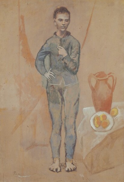 A pale, gray skinned young man stands next to a vase and plate of food against a pinkish-tan background in this loosely painted vertical painting on cardboard. The man’s body faces us but he looks down and slightly to our right with deeply shadowed eyes under dark brows. He has close-cropped, dark brown hair, a straight nose, and his full mouth is closed. He wears a slate-blue, fitted jacket over leggings, both painted with smudges of gray, dark green, and lilac purple, and some areas of the tan background show through. His feet are bare. The man’s left elbow, on our right, is bent so he holds his hand at his chest. The fingers of his other hand splay over his hip. Loosely painted and indistinct, a box-like form next to the man’s feet seems to be draped with a translucent white cloth. The box or table holds a tall terracotta vase behind a white dish. Four oval-shaped objects, painted with marigold orange and buttercup yellow, fill the plate and another sits on the cloth next to the dish. Sweeping but vague coral-peach lines and washes on the background suggest that the man may stand in front of a curtain. The artist signed the work “Picasso” in the lower left.