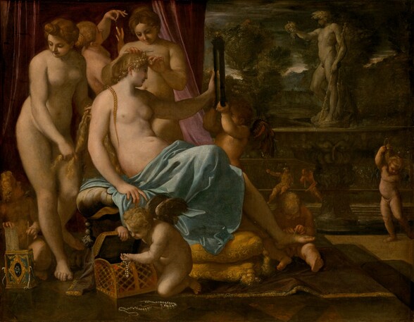 In the left half of this horizontal painting, a bare-chested, seated woman, Venus, is tended by three nude women and several child-like, nude, winged putti. All the women and putti have pale, peachy skin. To our right, a statue of a man stands on an ornately carved pedestal on a veranda in front of a distant landscape. Venus sits facing our right and she looks into a rectangular, black-framed mirror she holds up with her left hand. Her blond hair is braided and she has delicate features. A sky-blue cloth wraps around her waist and lap, and covers her legs. One foot rests on the lap of a seated putto, who ties on a sandal. Another putto helps hold up the mirror. A third putto near us, in front of Venus, pulls strings of pearls from a gold box and the fourth, in the lower left corner, lifts a comb and long needle out of a gilded, rectangular box. Two of the women behind Venus tend to her hair and the third holds up and gazes at a teardrop-shaped pearl. A dusky rose-pink curtain falls behind the women and putti. The view opens onto a terrace on the right half of the painting. A gray stone sculpture of a nude man holding up a bunch of grapes with one hand and bracing a tall stick with the other stands facing our left on an ornately carved base. The base is made up of a wide, shallow bowl above a single pedestal foot. In the distance, two people sit against a tall balustrade. The person on the left wears gold-colored armor, a helmet, and holds a long spear. The bearded man to the right appears to be nude as he leans to the side toward his companion, resting his hand and chin along a staff propped on the bench's seat. Trees and mountains in the landscape beyond are painted with brown, deep gray, and forest and sage green. A sliver of white sky along the horizon brightens an otherwise steel-gray sky.