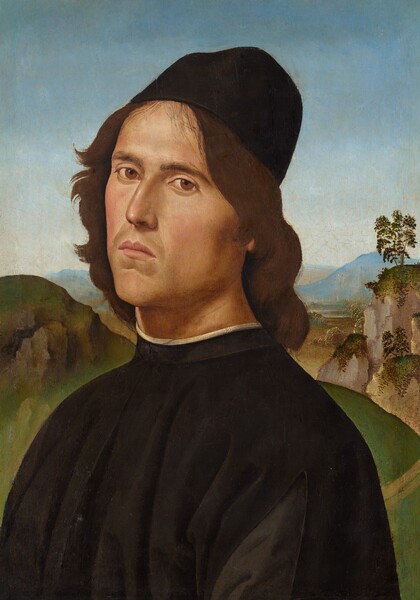 Shown from the chest up, a pale-skinned man with a narrow face looks at us from in front of a distant landscape in this vertical portrait painting. His body and face are angled to our left, so he looks at us from the corners of his brown eyes. He has dark, low brows, a straight nose, high cheekbones, and his rose-pink lips turn slightly down at the corners. Chestnut-brown waves fall over his ears and down the back of his neck from under a tall, brimless, rounded, black cap. His black robe has a high neck lined with a white undergarment. Far behind him, a grassy hill leads up to steep, rocky outcroppings, with those to our right dotted with trees. The land rolls into the distance to meet mountains, hazy blue along the horizon, which comes halfway up this composition. The clear sky above deepens from pale blue along the mountains to slate blue across the top.