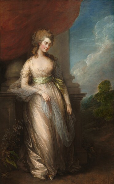 A woman with pale, smooth skin stands wearing a loosely draped, champagne-peach dress in this vertical portrait painting. Her body faces us but she turns her head to look down and off to our right with brown eyes. She has dark brows, an upturned nose, and her carnation-red lips are closed in a slight smile. Her ash-brown hair is loosely pulled up so it sweeps back from her face, while thick curls cascade down her neck and over her shoulders. Her long sleeved, floor-length dress is tied at her waist with a sage green sash. Gossamer white fabric drapes around her upper arms and she holds the long ends in both hands. Her right elbow, to our left, rests on the high base of columns that rise behind her and off the top edge of the canvas. A rust-red curtain drapes down from the top of the painting, over the columns. To our right, beyond the columns, the landscape opens to a view of trees beneath a watery blue sky with white puffy clouds.