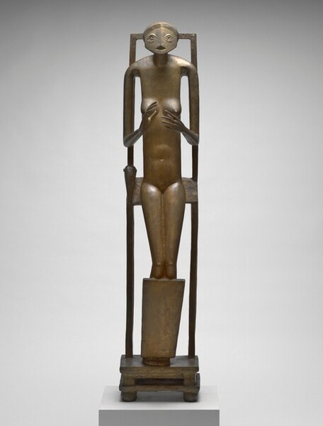 An abstracted, thin, nude woman with a rounded face seems to half-sit, half lean back against a tall, narrow chair in this golden, bronze sculpture. Her body faces us in this photograph. Her wide, oval face has two stylized, star-like eyes and a triangular opening for a mouth. The torso is tall and thin, and her limbs elongated. With thin arms, she holds up open hands with palms facing each other at the level of her round breasts. Her fingers are long and delicate. She is encased within a tall, rectangular frame. With knees slightly bent and seeming to rest against a panel that runs in front of her shins, she seems to lean against a slat against her backside, perhaps the seat to the stylized chair. Her feet are pressed together on a double-tiered, low, square base with four square feet at the corners.