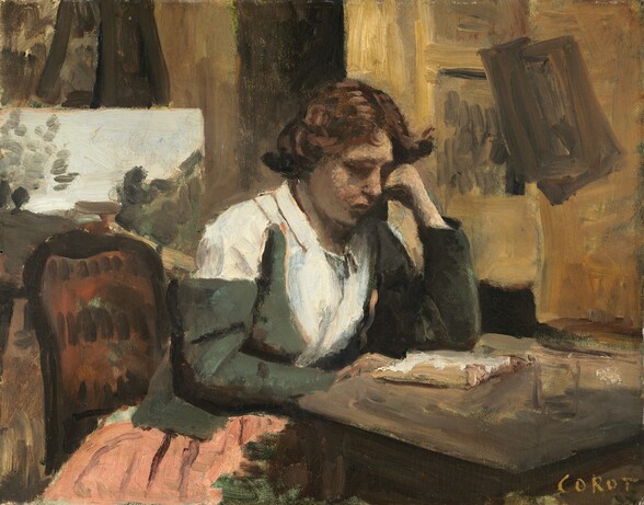 A pale-skinned woman sits at a table leaning over an open book in a brightly lit room in this loosely painted, horizontal scene. The woman is shown from the knees up, and she sits in the center of the picture with her body angled toward the table to our right. Her wavy, chestnut-brown hair is short or pulled back to either side of a center part. She wears a white shirt under a fern-green jacket. The sleeve on the arm closer to us has slipped down over her shoulder. The portion of her skirt we can see is pale peach with plum-purple stripes. She sits on a wooden chair with a curved and possibly upholstered rust-red back. She rests one elbow on the table and her cheek on that fist. She holds open the pages of a book with her other hand, at the edge of the brown table. The room beyond her has walls and possibly works of art painted with swipes of golden yellow, warm caramel, and dark brown. At first glance, a painting of a landscape could be mistaken for a window on the back wall, but then we notice the tall legs of the easel holding it. The artist signed the lower right, “COROT.”