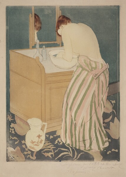 Created with areas of muted color, a woman with pale skin bends over a basin on a washstand in this vertical print. The edges of the woman’s body and clothing, the washstand, and bowl and bottles in front of her are outlined with dark brown or black lines. The woman’s body is angled to our left and away from us, so we see her bare back and her left arm as that hand dips into the water in the bowl. The bodice of her dress is loose around her waist, and her full skirt falls to the floor. The fabric is patterned with ivory-white, sage-green, and pale pink vertical stripes. She hunches over the basin so we see her left ear and the back of her lowered head. Her chestnut-brown hair is pulled up and back. The basin is cream white, and two glass bottles sit next to it, to our left. The washstand has a raised ledge around the sides and back. A rectangular mirror is mounted on the back edge, and the top of the woman’s head is reflected there. The washstand and edges of the mirror are peanut-brown, and the inset top surface of the stand is white. We look slightly down onto a white, handled pitcher on the floor in front of the left corner of the washstand. The pitcher has a wide opening, and tea-brown flowers are painted on the rounded body. The wall behind the washstand and the wall reflected in the mirror is muted slate blue. The carpet across the bottom of the composition is patterned with parchment-brown flowers and leaves against a darker, denim-blue background. At the bottom center edge of the printed image, a royal-blue C and M are overlapped. An inscription written lightly in graphite in the margin beneath the right corner of the printed image is difficult to make out.