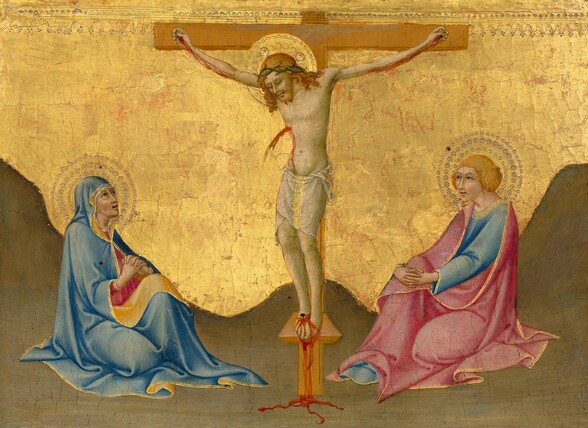 A man is nailed to a wooden cross, and two people sit, one to each side, on the sand-colored ground with their bodies angled inward, all against a gold background in this horizontal painting. All the people have pale skin with a greenish cast, and gold halos. The crossbar of the T-shaped cross nearly touches the top edge of the composition. On the cross, Jesus’s body and head are angled to our left. His head tips down, and his eyes are dark slits. Scarlet-red blood streams down his arms from nails in each hand and spurts from a gash over his right ribs. Blood pours from the nail pinning both feet to a shallow ledge down to the ground below. His wavy, honey-blond hair falls over his shoulders, and he has a full, forked beard. Touches of red indicate blood at the points of a ring of thorns around his head. He is nude except for a white loincloth lined with gold down the front around his hips. His body is thin, his ribs visible. The ground around the cross is painted a flat, brown color, which rises in a low mound behind the base of the cross, and up to each side to indicate hills. To our left, a woman sits with one leg folded under her, her other knee raised by her intertwined hands. She looks up at Jesus, her mouth parted and lined with wrinkles. Her brows are gathered over brown eyes. Her face is framed by a white veil, and the powder-blue hood and robe she wears over it is edged with gold. The underside is canary yellow where it turns back across her lap and down the sides of her face. Her raspberry-pink dress underneath is also trimmed with gold at the high neckline and cuffs. She and the person to our right both have rosy cheeks. The person to our right sits with fingers intertwined around one raised knee. That person has chin-length blond hair, a short fringe of bangs across the forehead, arched brows, a long nose, and delicate pink lips are parted. A sky-blue robe is covered with a rose-pink cloak, both edged with gold. The gold background behind all the people is visibly cracked and some areas of red show through. Across the top of the panel is a band of punched dots and incised lines to create a floral pattern. The halos are created with concentric bands of dots and rings punched into the gold background.
