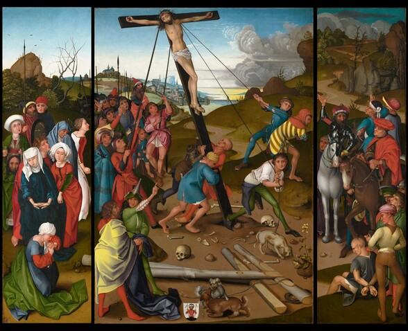 A wooden, T-shaped cross, with a man nailed to its crossbeam, is raised so it stands vertically as men and women look on against a grassy, hilly landscape in this horizonal painting. The painting is made up of three parts: a vertical rectangular panel at the center and a tall, narrow rectangular panel to each side. The people all have pale, ruddy, or tanned skin. The cross is being pushed up from behind by two men with poles and pulled up on the front side by three men pulling on two ropes. The man on the cross, Jesus, is nude except for a white cloth across his hips. Blood trickles from nails holding his hands in place, the single nail driven through both feet, and a ring of thorns across his forehead. His long brown hair hangs down over his shoulder, and he has a full, trimmed beard. His red-rimmed eyes slope downward as he looks down to the crowd below. His mouth is closed. The people in the crowd at the base of the cross wear dresses, robes, and turbans in shades of ruby red, grass green, lapis blue, pale yellow, carnation pink, and bright white. Three men push and pull on the base of the cross, driving it into a hole dug in the dirt ground. Eleven men and one child look on from our left, some with gaping mouths. One of the two men pulling on one of the ropes to our right wears tattered blue clothing, and his toes poke out of the shoe we can see. The other man there is barefoot and has a prominent hooked, red nose and a pointed beard. A red cowl covers his head over a tunic striped with lemon yellow and brown. An inscription on that man’s sleeve reads, “OHAIR.” Two men stand in the lower left corner of this panel. One looks at the cross and the other looks out at us, while pointing up to Jesus. Two human skulls and other bones litter the ground around the cross. Two more wooden crosses and some rope lie on the ground near us. Two dogs romp together nearby, next to a coat of arms showing a crowned man wearing a red robe and holding two pointed staffs. In the panel to our left, a woman wearing an azure-blue robe, Mary, interlaces her fingers and flips her hands palm-down, as she looks at the ground. Another woman in front of her kneels and holds her interlaced hands up by her face, elbows high. A woman and a cleanshaven man stand near Mary, and to our left, a woman wearing emerald green holds a cloth with Jesus’s face on it. Four more men and women look on, the women crying. In the panel to our right, a man in a red robe and a man wearing armor sit on horses. The armored man gestures up at Jesus. Two more men sit on horses behind this pair, and six stand among and in front of the group. Two men sit, one with his hands tied behind his back, near the lower right corner of this panel. The bound man is bald and looks down. The man behind him has a brown beard and hair, and looks up at Jesus. Across all three panels, the scene takes place on a smooth, dirt ground. Grassy hills rise beyond the cross to higher peaks in the left and right panels. Paths or roads wind into the distance to a town on the horizon, which comes about two-thirds of the way up the composition. Hazy in the distance, a city wall encloses steeples and buildings, and a bridge spans a body of water leading up to the city. Gray clouds begin to tumble across the sky from our right. The sky is nearly white along the horizon and deepens to watery blue along the top edges of the panels.