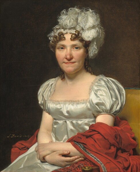 Shown from the lap up, a woman with peachy skin, wearing a white silk dress and feathered headpiece, sits facing and looking at us in a harvest yellow upholstered chair in this vertical portrait. She has blue-gray eyes and a rounded, slightly pink nose. Her thin lips are closed and pulled back with shallow dimples at the corners of her mouth. Chestnut brown ringlets frame her face and fall to her shoulders under a white hat or headband covered with curling, billowing white feathers. Light reflecting off the cloth of her high-waisted dress suggests that it is silk or satin. It has a lace-lined square neckline and puffed short sleeves. She crosses her arms at the wrist and her hands rest in her lap, holding opposite forearms. A red shawl with silver and blue trims wraps over her left arm, on our right, and bunches up behind her against the yellow chair. The artist signed and dated the work in yellow paint against the dark background behind the woman: “L. David 1813.”