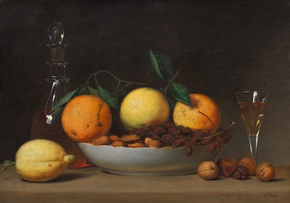 A shallow bowl filled with oranges, grapes, and nuts is surrounded by a short, flaring glass, a glass decanter, a lemon, and more nuts arranged along a wooden tabletop in this horizontal still life painting. Seeming close to us, the objects nearly fill the composition, and the table extends off both sides. The three oranges are pale, with the one at the center nearly yellow, and a stem of dark green leaves lies across the top. A bunch of shriveled grapes, like raisins still on the vine, lies across the almonds and other nuts, all in their shells, in the bowl. The outside of the bowl is white, and it has a gently scalloped rim. A lemon sits to our left of the bowl of fruit, and behind it, the glass decanter has a teardrop-shaped glass stopper. Light coming from the front and our left makes the peachy liquid glow where we see the bottom of the decanter between the lemon and the bowl. To our right are four whole walnuts in their shells, with a few grapes hanging from the bowl. Behind the walnuts, a long stemmed, flaring, clear glass is almost filled with a peach-colored liquid. The background is deeply shadowed at the upper left, lightening slightly to elephant gray toward the lower right. The artist inscribed the painting as if he had written his name, date, and location on the front edge of the table, near the lower right corner: “Raphaelle Peale Aug: 5th 1814 Philad:”