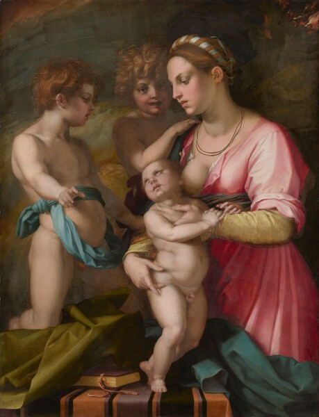 Two nude young boys and a young woman holding a standing infant are tightly grouped around a table, almost filling this vertical painting. They all have fair skin tinged with pink. The woman is seen from the knees up, and she stands at the front, right corner of the table, which spans most of the composition. Facing our left in profile, her auburn hair is pulled back and wrapped with a slate-blue ribbon, and is wound around the crown of her head. She looks down with dark eyes under thin brows. She has a long nose, and her full, dusty rose-pink lips are closed. Two thin cords hang like necklaces just above the neckline of her carnation-pink gown, which is unbuttoned to reveal one bare breast. The infant’s plump body stands at the center of the group. The woman holds him close to her body, but he turns his face away to look at the young boy on his right, our left. That child faces our right in profile and has wavy, copper-red hair. He is nude except for a blue sash that is tied once tightly around his waist and then wrapped so a loose hoop hangs down over his belly. His right knee, closer to us, rests on an olive-green cloth crumpled on the table beneath him. He leans back slightly, with his belly pushed forward, and looks down at the infant while pointing to us with his closest hand. A third child, with unruly honey-blond hair, stands facing us from the back of the group, so is seen between the woman and the pointing child. The child at the back of the group touches the woman’s shoulder with one hand, looking straight at us with mouth slightly open. A burgundy-red sash is visible around the waist. Near the bottom edge of the painting, the tabletop is covered with a pumpkin-orange cloth striped with mauve-purple and black. A book rests near the baby’s feet and is partially covered by the green cloth to our left. A peacock-blue cloth is bunched on the right half of the table and hangs off that side, obscuring the woman’s knees. The background is painted with broad strokes and swirls of caramel and flax brown and flint blue, with flickers of red and gold in the upper right.