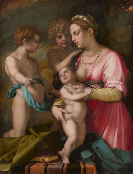 Two nude young boys and a young woman holding a standing infant are tightly grouped around a table, almost filling this vertical painting. They all have pale skin tinged with pink. The woman is shown from the knees up, and she stands at the front, right corner of the table, which spans most of the composition. Facing our left in profile, her auburn-brown hair is pulled back and wrapped with a slate-blue ribbon, and is wound around the crown of her head. She looks down with dark eyes under thin brows. She has a long nose, and her full, dusty rose-pink lips are closed. Two thin cords hang like necklaces just above the neckline of her carnation-pink gown, which is unbuttoned to reveal one bare breast. The plump infant stands at the center of the group. The woman holds him close to her body, but he turns his face away to look at the young boy on our left. That child faces our right in profile and has wavy, copper-red hair. He is nude except for a blue sash, which is tied once tightly around his waist and then wrapped so a loose hoop hangs down over his belly. His right knee, closer to us, rests on an olive-green cloth crumpled on the table beneath him. He leans back slightly, with his belly pushed forward, and looks down at the infant while pointing to us with his closest hand. A third child, with unruly honey-blond hair, stands facing us from the back of the group, so is seen between the woman and the pointing child. The child at the back of the group touches the woman’s shoulder with one hand, looking straight at us with mouth slightly open. A burgundy-red sash is visible around the waist. Near the bottom edge of the painting, the tabletop is covered with a pumpkin-orange cloth striped with plum-purple and black. A book rests near the baby’s feet and is partially covered by the green cloth to our left. A peacock-blue cloth is bunched on the right half of the table and hangs off that side, obscuring the woman’s knees. The background is painted with broad strokes and swirls of brown and flint blue, with flickers of red and gold in the upper right.