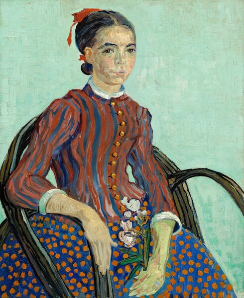 Shown from about the knees up, a young woman sits in a chair angled to our right but she turns her face to look at us in this loosely painted, vertical portrait. Her chair has a rounded back and arms made from what looks like bent, woody vines, and the background is a solid field of pale aqua. Her dark hair is parted in the middle and tied at the nape of her neck with a red ribbon. Dark eyebrows curve over brown eyes, and she has a rounded nose, and her petal-pink lips are slightly parted. Her pale peach skin is tinged with green on her face and hands. Her right arm, on our left, rests along the arm of the chair. In her other hand, which rests in her lap, she holds a sprig of blooming oleander, with light pink flowers and green leaves. The bodice of her high-necked dress is striped with brick red and royal blue, and is lined with a row of round gold buttons down the front. The sleeves come down to her forearms and the cuffs and collar at her neck are white. Her full skirt is royal blue with pumpkin-orange dots. The brushwork is loose throughout and individual brushstrokes are visible, especially in the stripes of her bodice and the patchy peach tones that make up her skin.