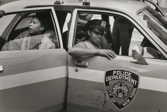 On a warm July day neighborhood children play in a patrol car, New York City