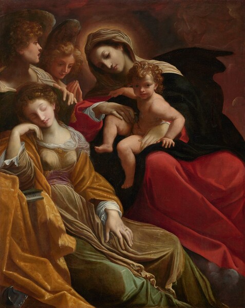 A young woman sleeps with her cheek resting on the back of one hand next to a woman holding a nude baby and two winged angels in this vertical painting. All the people have pale skin and they nearly fill the composition. The sleeping woman, Saint Catherine, rests her elbow on a stone table covered by a golden yellow cloth, which also wraps around her shoulders. Her knees are angled to our right and her face tips onto her hand to our left. Her curly, light brown hair is pulled back. She has delicately arching eyebrows, a straight nose, and her pink lips are closed. Her pale, olive-green, floor-length dress is tied at the waist with a mauve-purple sash. She wears a gold ring with a gray stone on the third finger of her left hand, which rests in her lap. To our right, the second woman, Mary, leans over Saint Catherine. Mary’s head is angled to our left, toward the sleeping saint, and she looks to our right, down past the baby. Mary’s complexion is has a faint gray cast, and her brown hair is covered by a white cloth, which is surrounded by a halo of light. A dark garment covers her shoulders over a scarlet-red dress. The baby sits on Mary’s lap with his body facing our left, toward Saint Catherine. He leans our way and looks at us with dark eyes. Light catches his brown curls and he has chubby cheeks, arms, and legs. Along the bottom edge of the canvas, a puff of gray cloud near the lower right corner seems to support Mary’s feet. A curving, charoal-gray spike in the lower left corner of the painting is partially covered by the yellow drapery. Behind Saint Catherine and over her head, next to Mary, are two winged angels with dark blond, curly hair. The angel closer to us rests one hand on the pine-green pillow behind Saint Catherine’s head and turns to look past Mary in profile, lips parted. The angel behind looks down with hands together in prayer. Light falls across the scene from our right. The upper right corner behind Mary is filled with brick-red clouds that, upon closer examination, are filled with faces looking onto the scene.