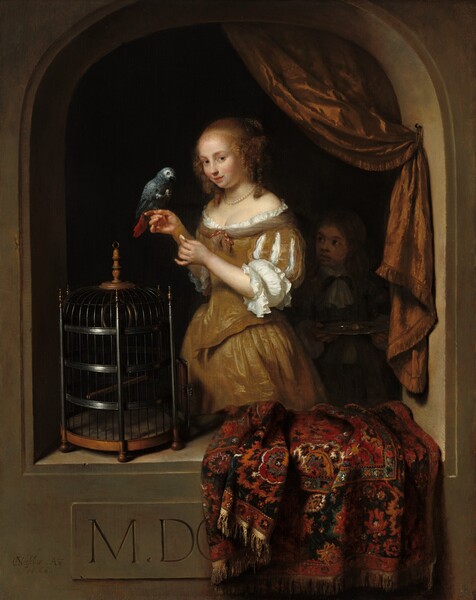 Shown from about the knees up, a pale-skinned young woman stands within a stone niche, with a parrot perched on her finger as she gazes out at us in this vertical painting. The woman’s hands are raised to chest height, and she balances the spruce-blue parrot on the index finger of her far hand while her other hand holds an indistinct, white object. Her body is angled to our left, and she looks at us from the corner of her green eyes under faint brows. Her round face has a small nose, flushed cheeks, and her coral-red mouth curls up in a slight smile, her lips parted. Her honey-blond hair is gathered at the back of her head with curly tendrils framing her face and falling to her shoulders. She wears a golden-brown gown trimmed with a narrow ruffle of white fabric along the low neckline that reveals her décolletage. The bird faces the woman and lifts something, presumably a bit of food, up with one dark claw. The underside of its tail is crimson red. A light-skinned boy stands in deep shadow just to the right of the woman. He looks up at her and holds a silver tray in both hands. They stand within a light brown, arched, stone opening beyond a ledge, which comes up to about the woman’s knees. A carpet patterned with stylized flowers in ruby red, burnt orange, teal blue, white, and black is bunched up and draped over the parapet, to our right. A tall, iron-gray cage sits to our left. The rug partly covers an inscription on the front face of the niche that reads, “M. DO,” with the O cut off. A copper-colored, fringe-lined drapery hangs from the upper right of the arch and is fastened to the inner edge of the opening to create a swag. The woman is brightly lit from the upper left, and the space behind her and the boy is ink black. The artist signed and dated the lower left corner as if he had carved into the front face of the arch. It reads, “CNetscher .Ao. 16.66,” with the C and N overlapping to make a monogram.