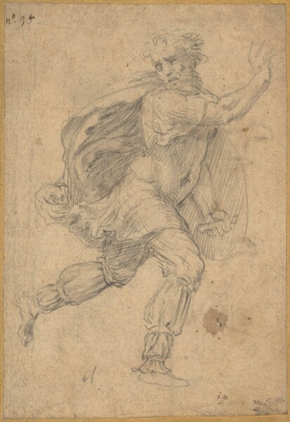 Drawn lightly with black chalk on tan-colored paper, a man runs to our right, lifting his right arm and looking back over his right shoulder so he faces us in this vertical drawing. His left leg, farther from us, is raised as he runs. A few lines suggest short curly hair and a beard, shadowed eyes, and his lips seem slightly parted. His thigh-length cape billows behind him, to our left, and he wears a fitted tunic or breastplate and pants cinched at the knee, calf, and ankle. He holds a round shield on his left arm. An annotation in ink in the top left corner reads, “no. 94.” A notation in the lower right, also in ink, reads, “i.91” near a seal or crest that appears to have been stamped in black ink.