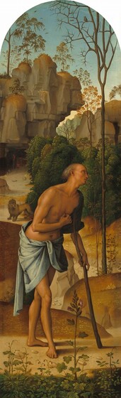 A man stands, leaning on a staff used like a crutch, in a deep, rocky landscape in this round-topped vertical painting. The cleanshaven man has tanned skin and sparse gray hair. He is nude aside from a slate-gray cloth that wraps around his hips. The hand not bracing the crutch is held in a loose fist at his chest. A few plants grow and bloom along the bottom of the panel. The dirt path on which the man stands winds through low, grass-covered mounds to a cave opening at the base of a tall, steep cliff face. A lion stands on the path between the man and the cave. An owl perches in the bare, spike-like branches of a spindly tree growing to our right of the man.