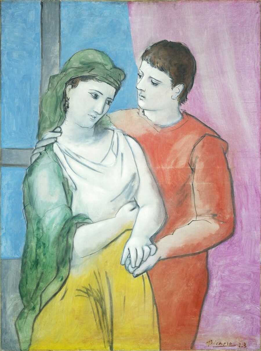 Shown from the hips up, a woman and a man stand side-by-side in front of a window and curtain in this vertical painting. The people and background are painted with mostly flat areas of vivid color, with their bodies and features outlined in black. The man and woman both have paper-white skin, brown hair, straight noses, and small mouths. They stand facing us so the woman’s shoulder slightly overlaps the man’s. The man’s right arm wraps around the woman to rest on the far side of her neck. She holds his left hand with her left hand, both to our right, and her other arm is tucked into her waist. The woman’s head tilts to our right, toward the man, while her shoulders slope slightly away to our left. She looks off to our right with dark eyes under thin brows. Her white shirt is the same color as her skin. A sea green-cloth drapes over her head and one shoulder, and her skirt is buttercup yellow. The man turns his head to look at the woman. His clothing is coral red. The couple stands in front of a mauve-purple curtain on our right and a window with baby-blue panes set within an ash-gray frame on our left. The artist signed the painting in brown in the lower right, “Picasso 23.”